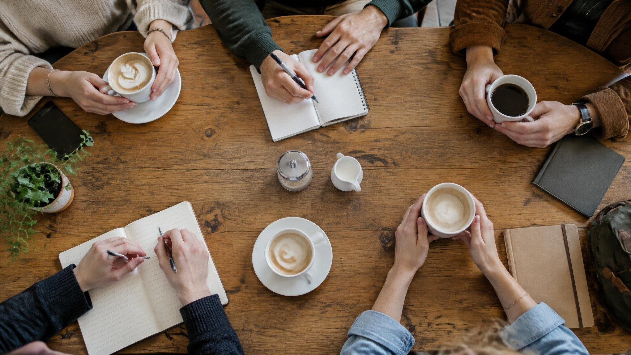Group of friends sitting around a table in a cafe seen from above